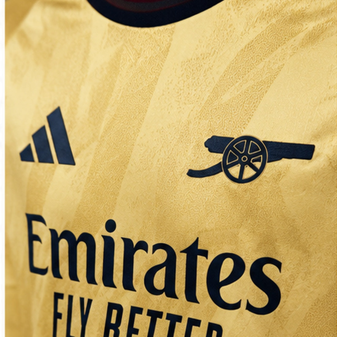 Gros plan maillot Arsenal Third 2026-2027 doré, écusson canon et détails Adidas